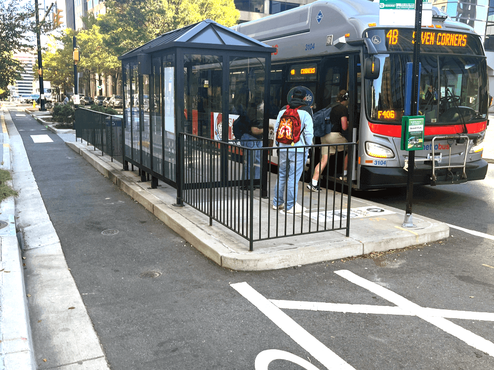 Bus stop island with passengers getting on bus next to a bus lane.