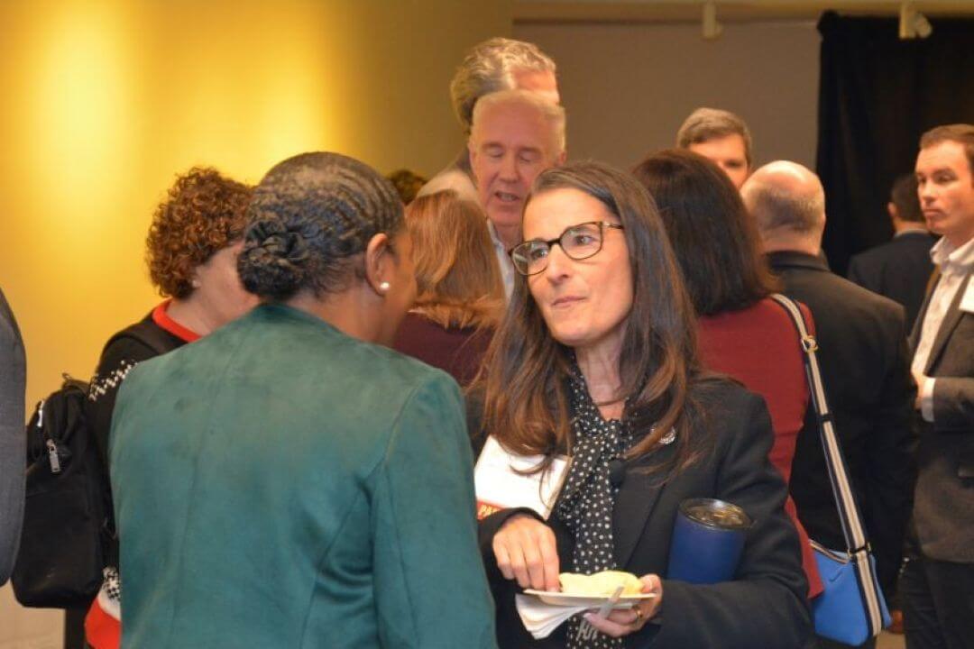 Two business women in crowd having conversation.