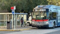View of bus stop with person waiting at get on Metrobus.