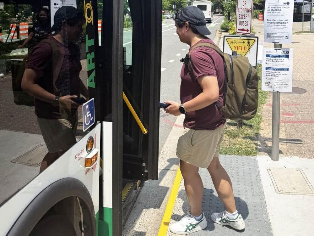 Bus rider getting on bus from a bus stop with safety features like yellow curb marking bumpy concrete strip.